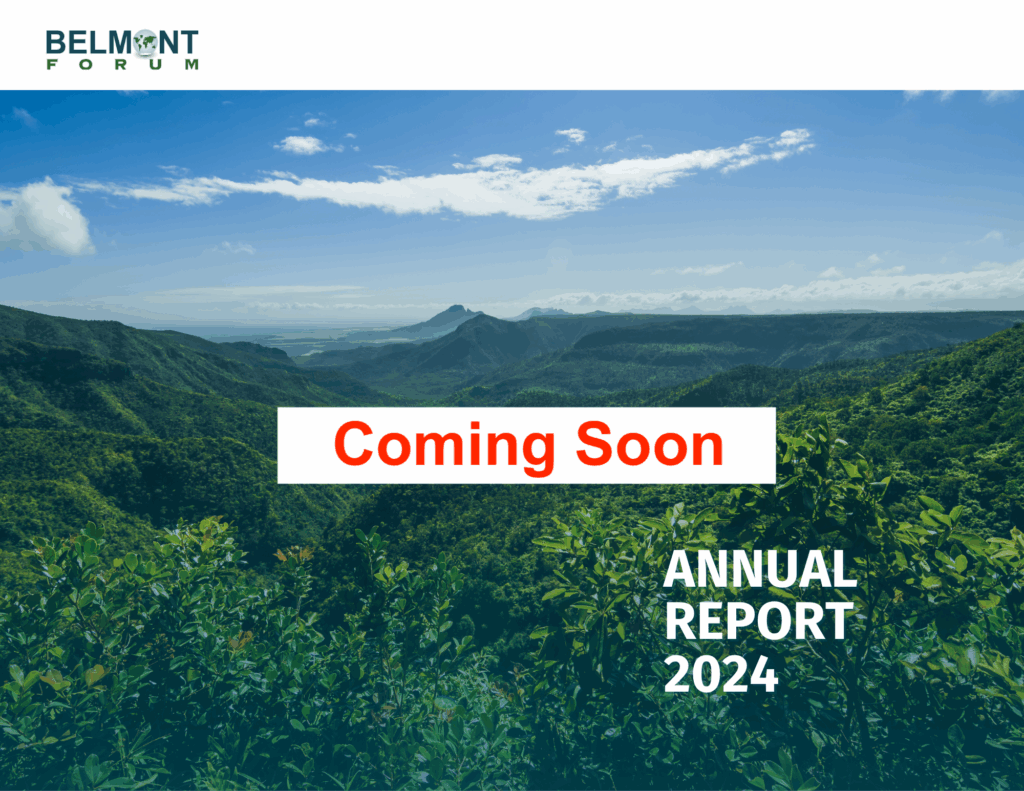 Promotional cover for the Belmont Forum Annual Report 2024. A lush, green mountainous landscape is shown under a blue sky with scattered clouds. In the center, a white box with bold red text reads “Coming Soon.” At the bottom right, white text reads “Annual Report 2024.” The Belmont Forum logo is at the top left.